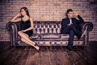 Man and woman sitting far apart on sofa [Image © oneinchpunch - Fotolia.com]